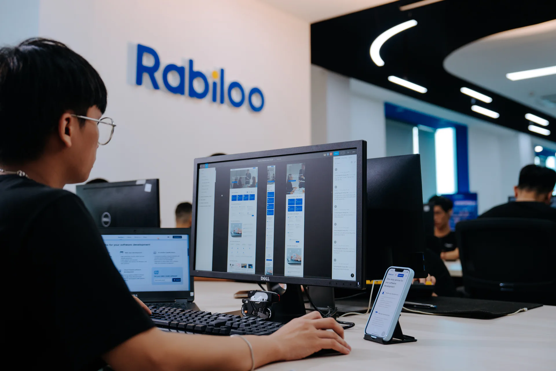 Rabilooのエンジニアが、開発中のWebサイトをモニターとスマートフォンで確認する様子