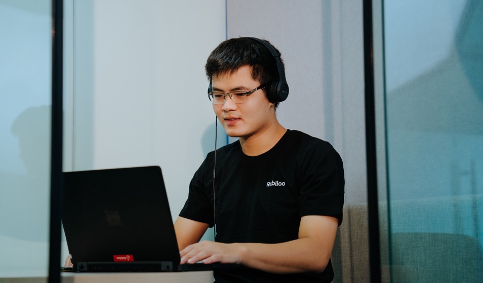 ヘッドセットを着けてノートPCに向かい、離れた相手と話しながら進行を確認しているRabilooのメンバー